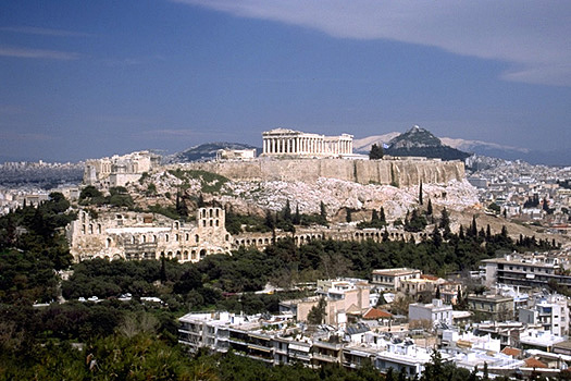 View of the Acropolis and the South Slope from the southwest (from near the Philopappos Monument). - In the background to the right of the Parthenon are Mt. Lykabettos and Mt. Penteli. Photo taken in 1998. by Kevin T. Glowacki and Nancy L. Klein