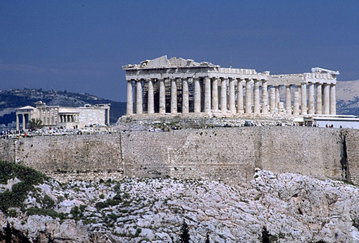 View of the Erechtheion, the Parthenon, and the south wall of the Acropolis. - View from the southwest (from near the Philopappos Monument). In the background to the right of the Parthenon are Mt. Lykabettos and Mt. Penteli. Photo taken in 1998. by Kevin T. Glowacki and Nancy L. Klein